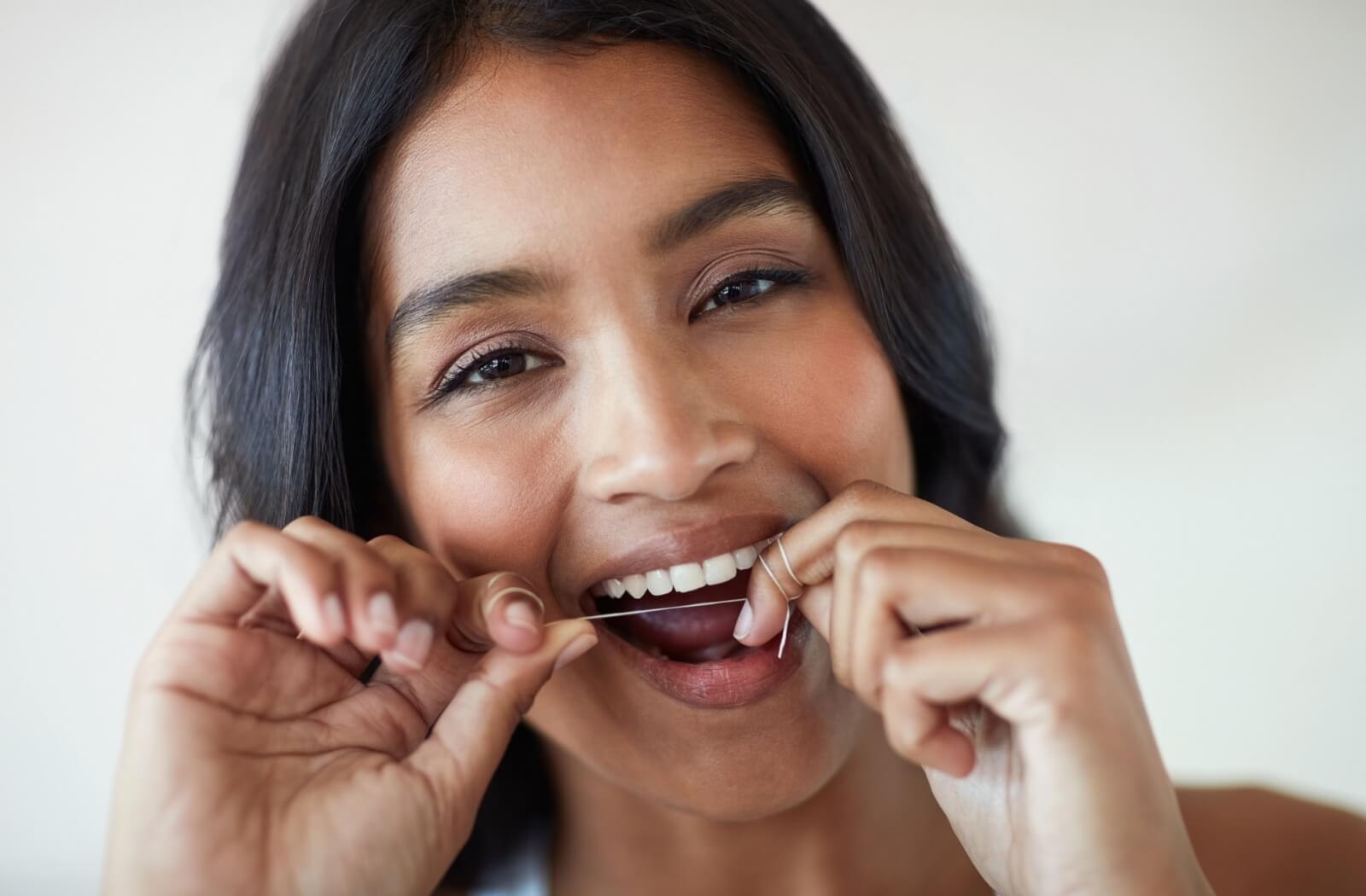 Woman with dark long hair flossing.