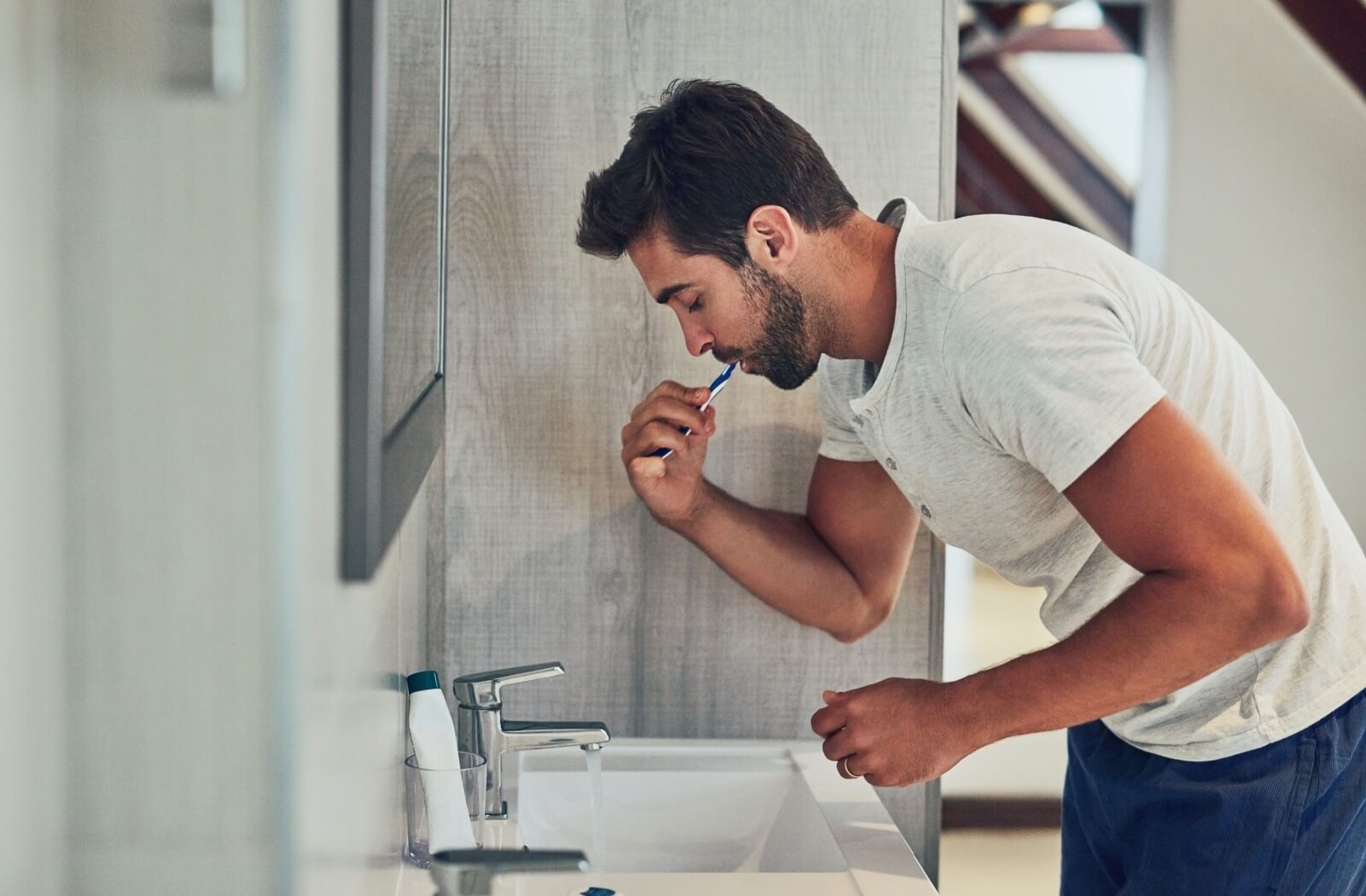 A person brushes his teeth in the bathroom mirror as part of his daily oral hygiene routine.