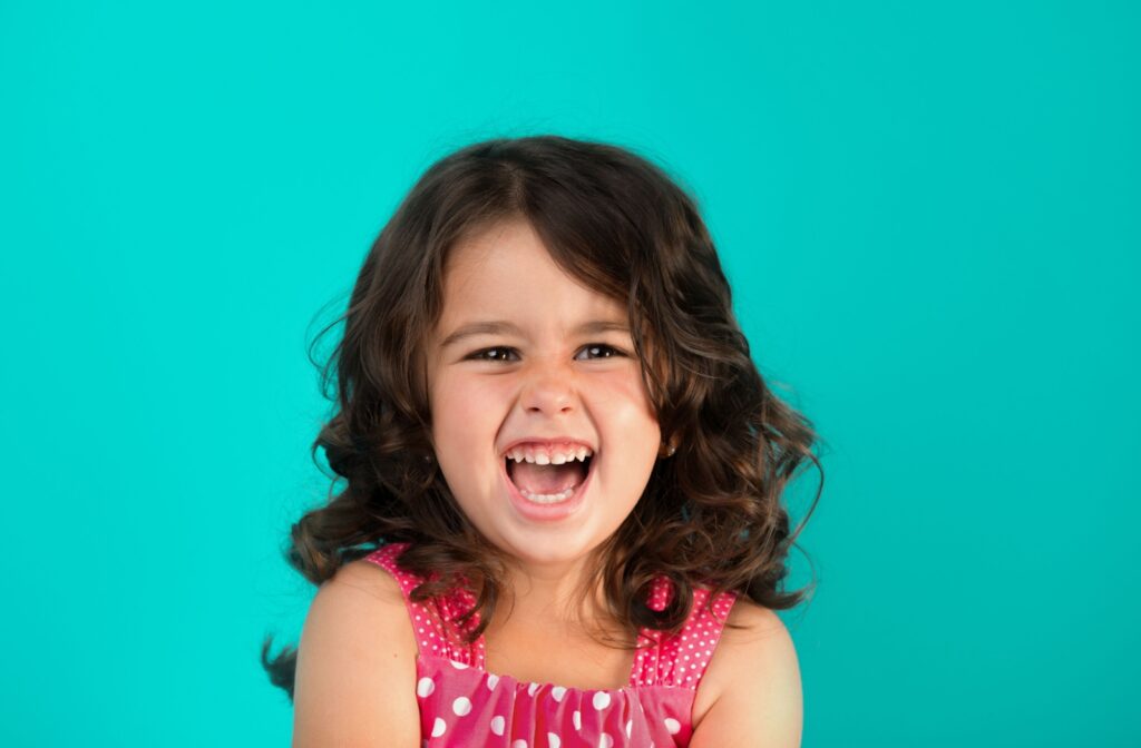 A child in front of a blue background laughing
