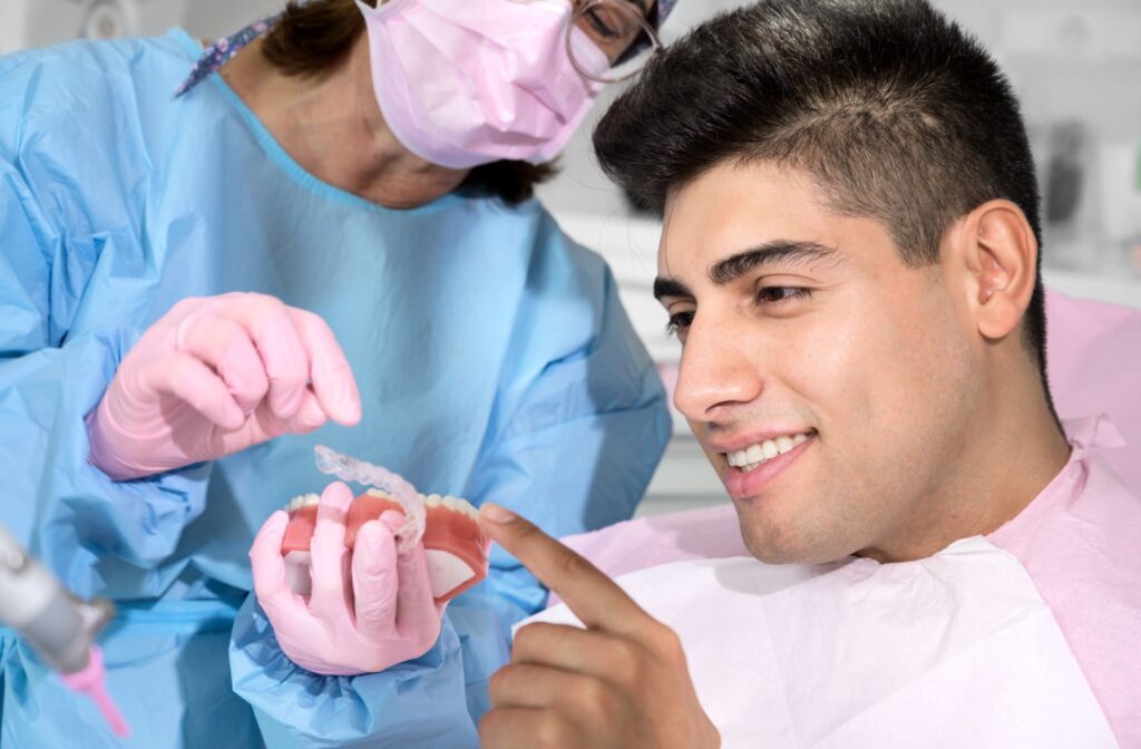 A dentist uses a dental model to show how their patients' aligner trays will shift their teeth into the correct position.