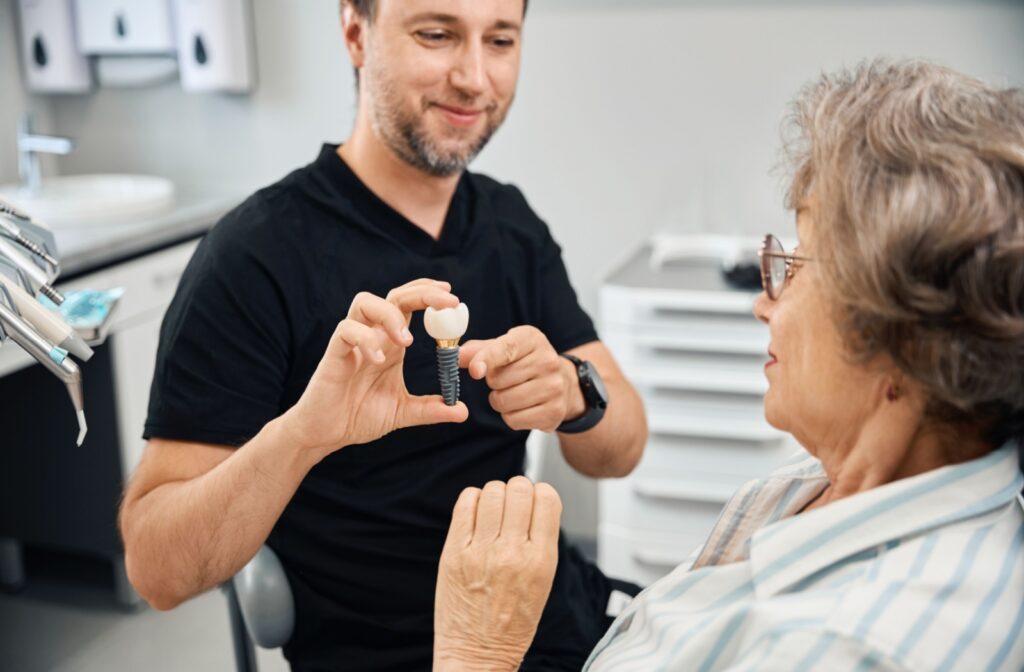 a dentist showing a patient a model of a dental implant