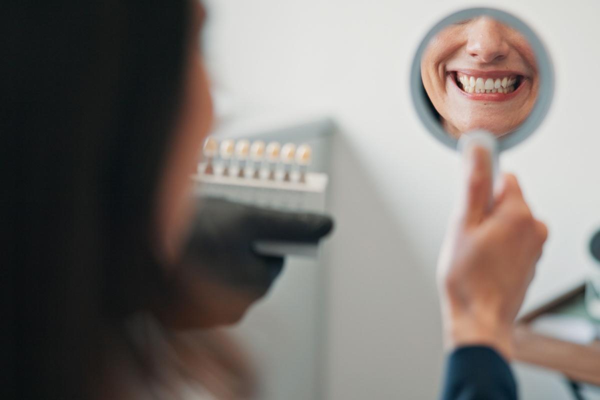 a person looking in a small mirror and smiling while at the dentist